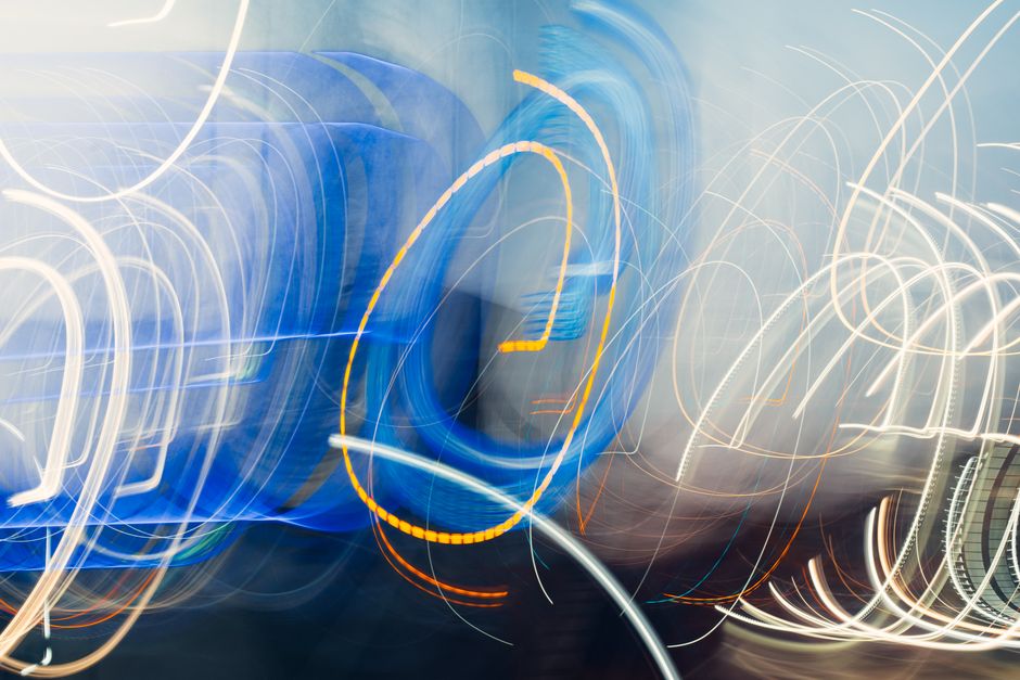 Abstract light trails creating dynamic movement with vibrant blue and orange hues.