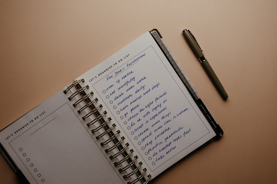 An open notebook on a brown background featuring handwritten New Year's resolutions.