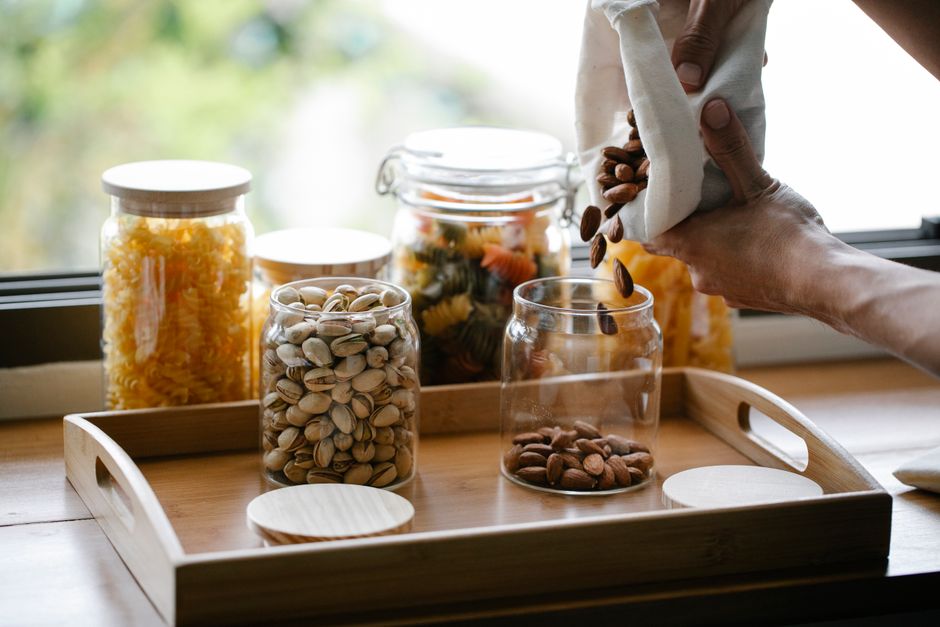 Discover sustainable kitchen storage using reusable bags and glass jars on a wooden tray.
